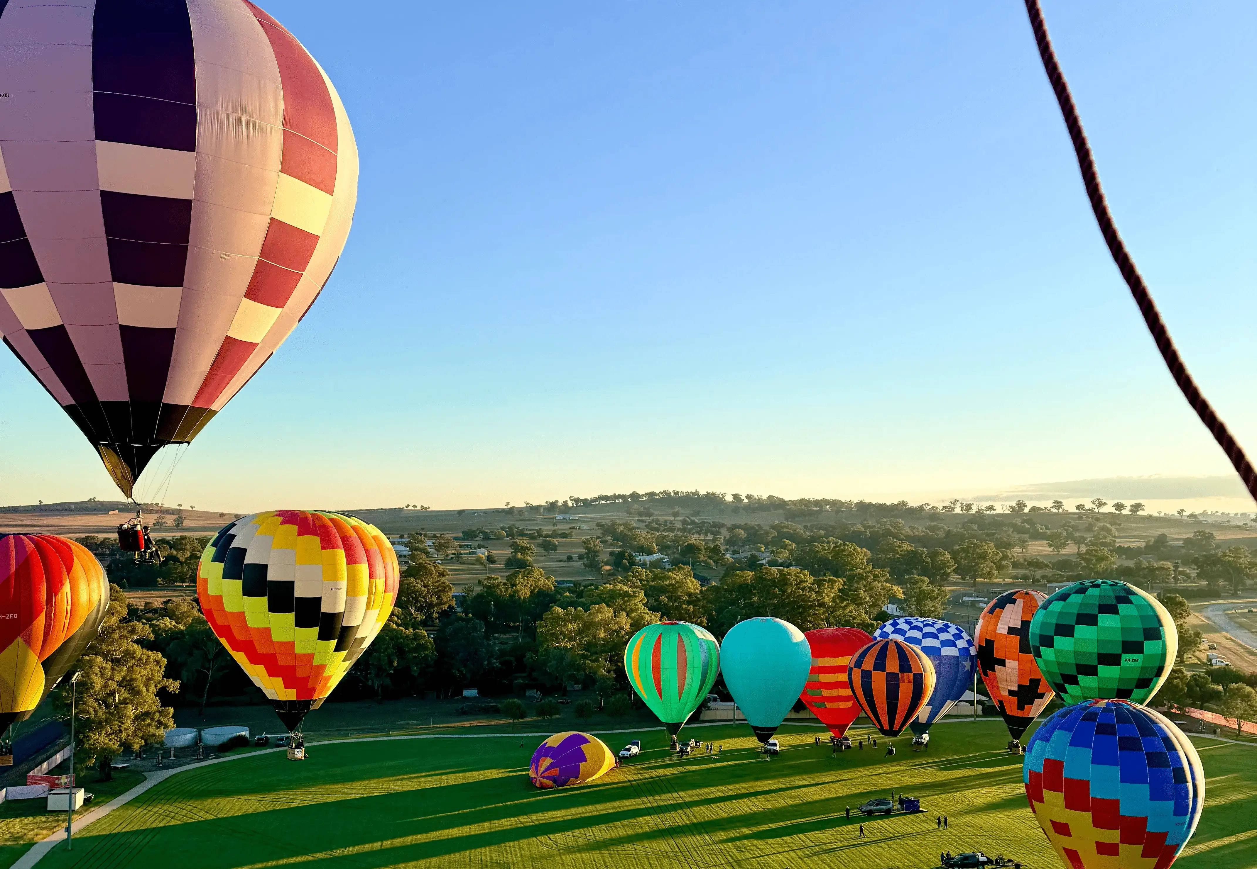Colourful hot air balloons taking off across a wide green field